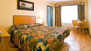 Habitación de hotel con una cama grande, un escritorio con sillas, un teléfono y una ventana con cortinas.