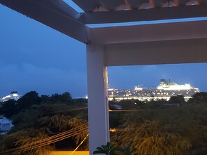 A balcony with a view of a cruise ship at night. - Mustique Suites Curacao (Willemstad)