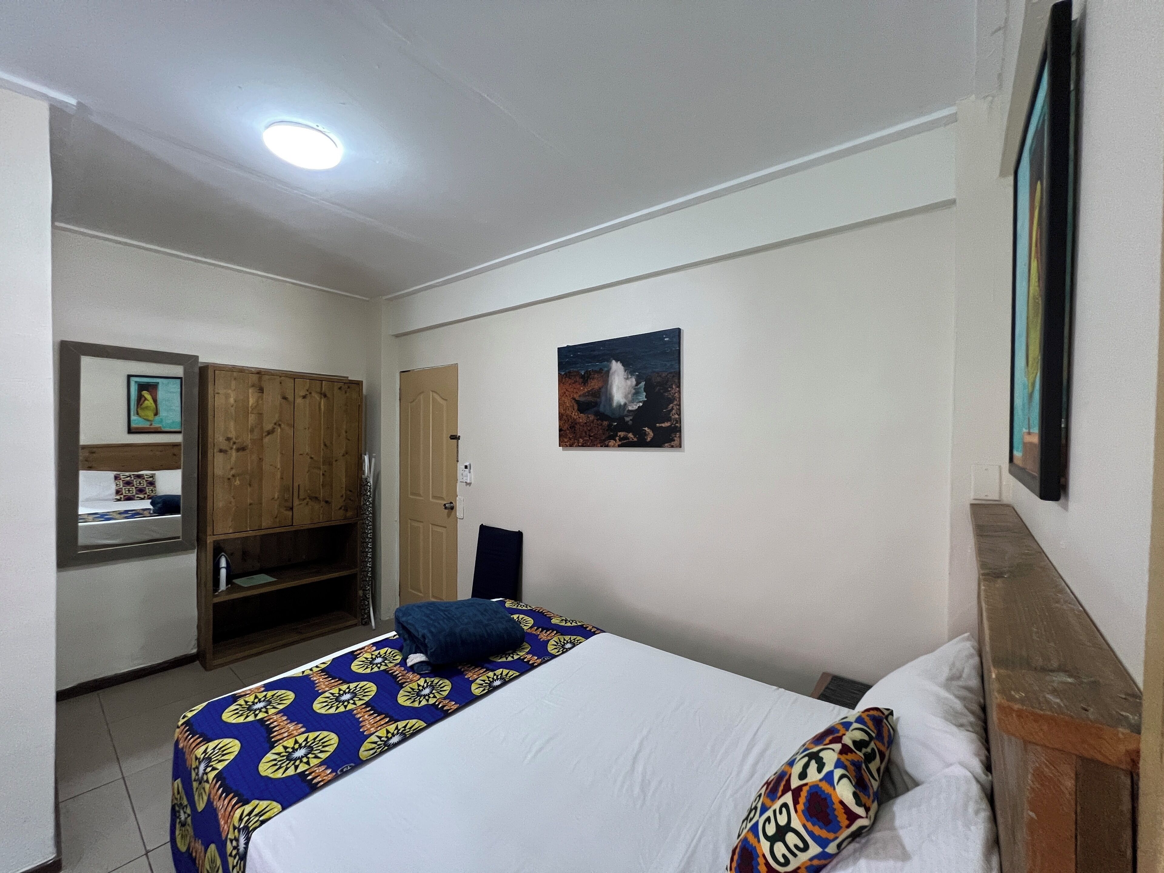 Un dormitorio con cama, un armario de madera, un cuadro y una puerta.
