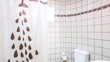 A bathroom with a shower curtain, toilet, and bathtub.