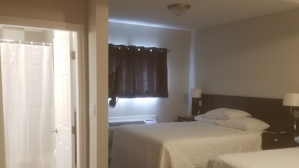 A hotel room with two beds, a bathroom with a shower curtain, and a ceiling light. - Mount View Motel (Oliver)