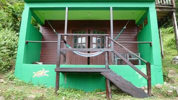 A wooden structure with a green exterior, a wooden staircase, and a hammock.