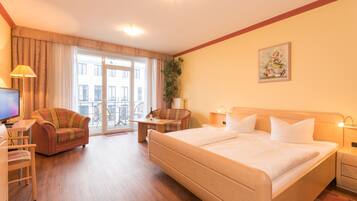 Ein Hotelzimmer mit einem großen Bett, einem Schreibtisch mit Stuhl, einer Couch und einem Fernseher.