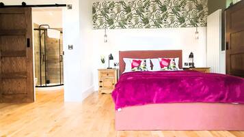 A bedroom with a large bed, wooden floor, a sliding door, a nightstand, and a wall with a leafy pattern.