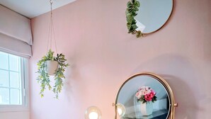 Un tocador con un espejo redondo, dos luces empotradas en la pared y una planta en maceta.