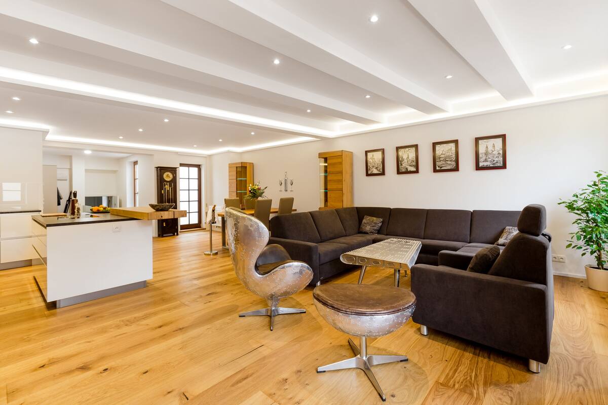 A modern living room with a dark brown sectional sofa, a glass coffee table, and a unique metal chair.