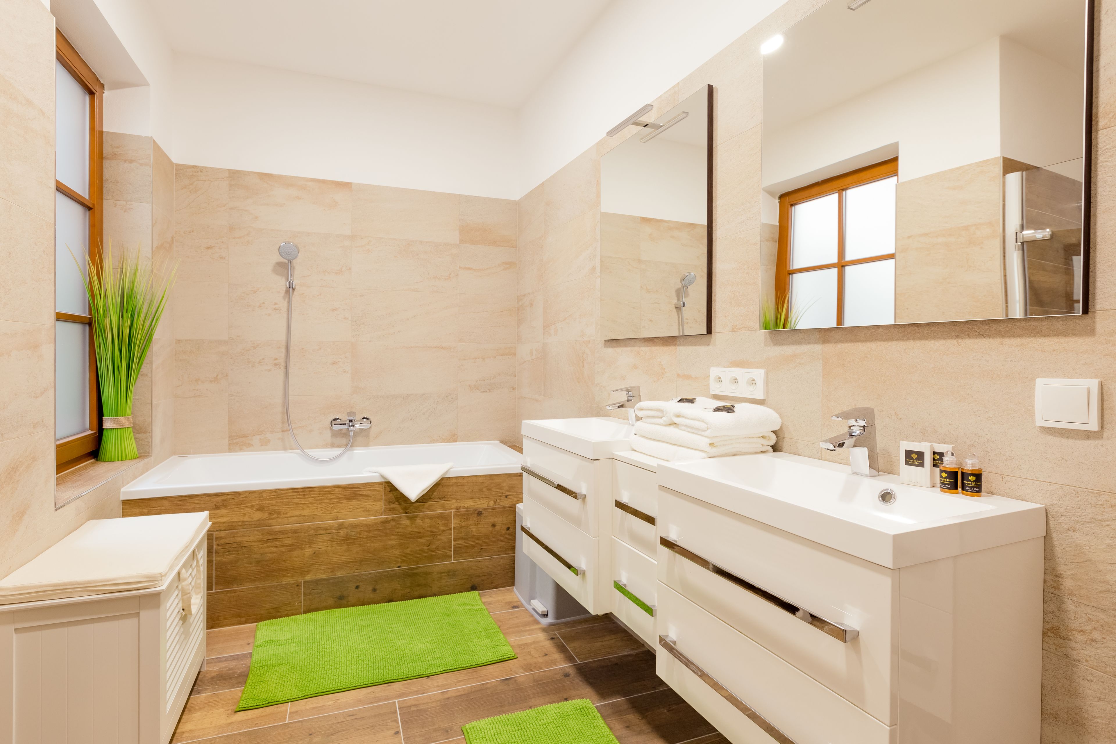 Un baño moderno con bañera, un espejo grande y un lavabo.