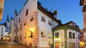 A historic building with a traditional European architectural style, featuring a prominent tower and a well-lit entrance. - Hotel Zlaty Andel (Cesky Krumlov)