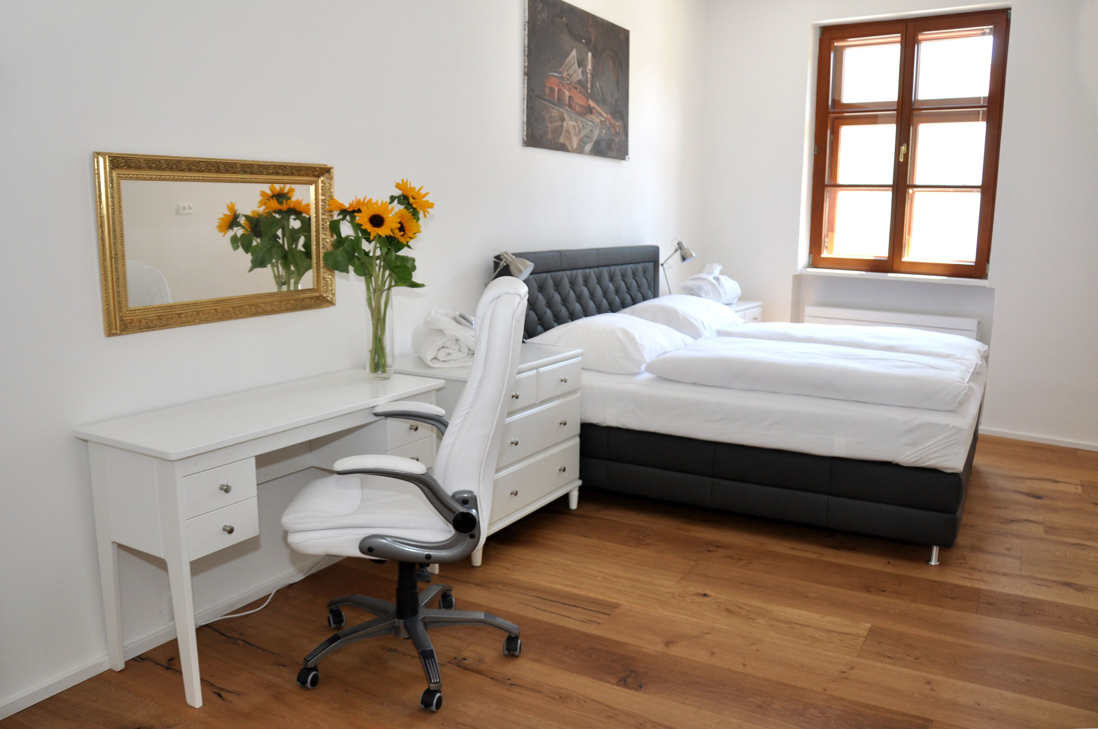 Un dormitorio con cama, escritorio, silla y ventana.
