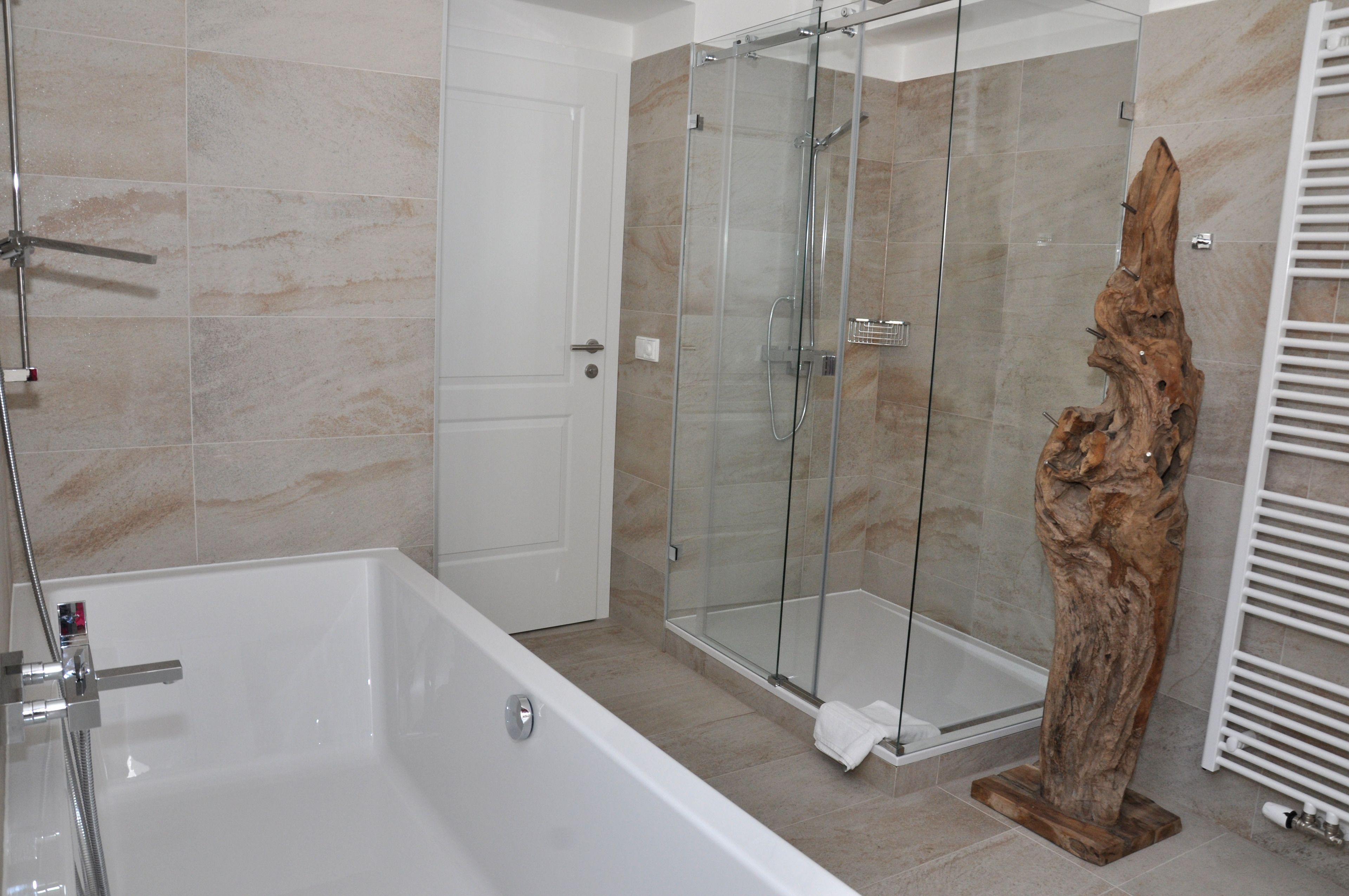 Un baño con ducha de vidrio, una bañera y una escultura de madera.