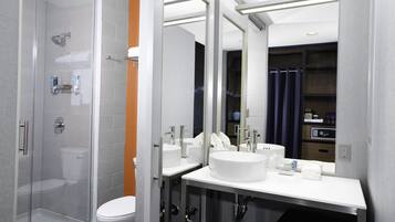 Un baño moderno con cabina de ducha de vidrio, inodoro blanco y tocador doble.