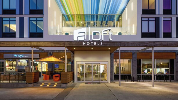 Ein Hotel mit moderner Gestaltung, Glasfassade und farbenfroher Decke.