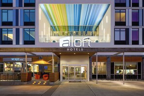A hotel entrance with a modern design, glass doors, and a colorful ceiling. - Aloft by Marriott Durham Downtown (Durham)