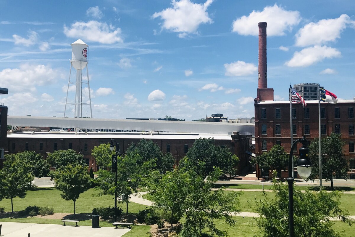 A large industrial building with a water tower, a tall chimney, and a flagpole with flags.