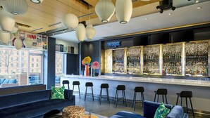 Eine moderne Bar mit Bartresen, Hockstühlen und einer Sitzecke mit Sofas und einem gemusterten Hocker.