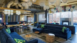 Ein stilvoller Lounge-Bereich mit blauen Sofas, runden Tischen und hängenden Papierlampen.