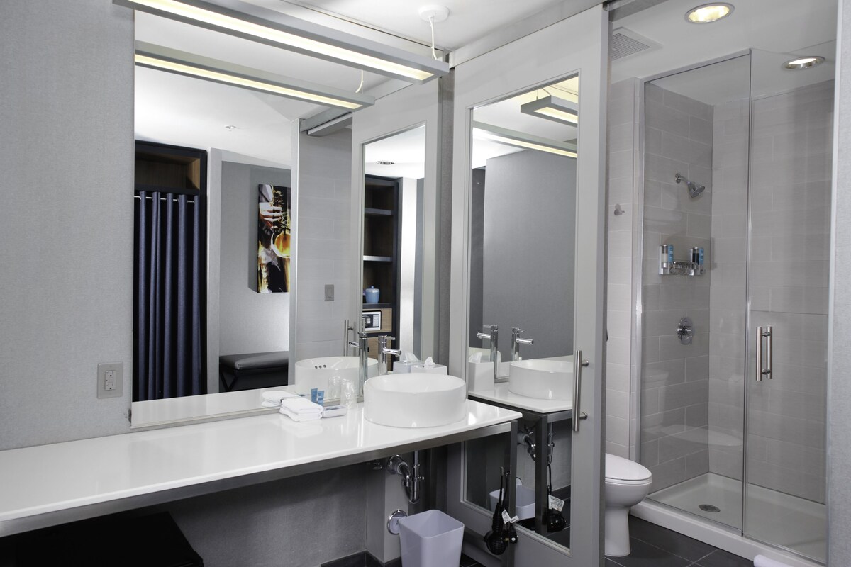A modern bathroom with two sinks, a toilet, and a glass-enclosed shower.