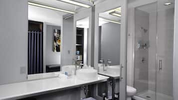 Un baño moderno con dos lavamanos, un inodoro y una ducha con mampara de vidrio.