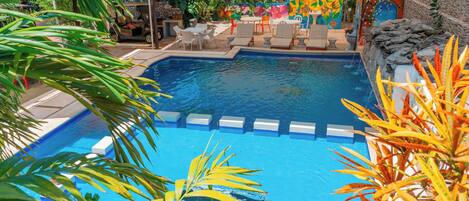 A swimming pool with lounge chairs and a tiled deck area.