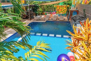 A swimming pool with lounge chairs and a tiled deck area. - Villa Pajaros (Isla Mujeres)