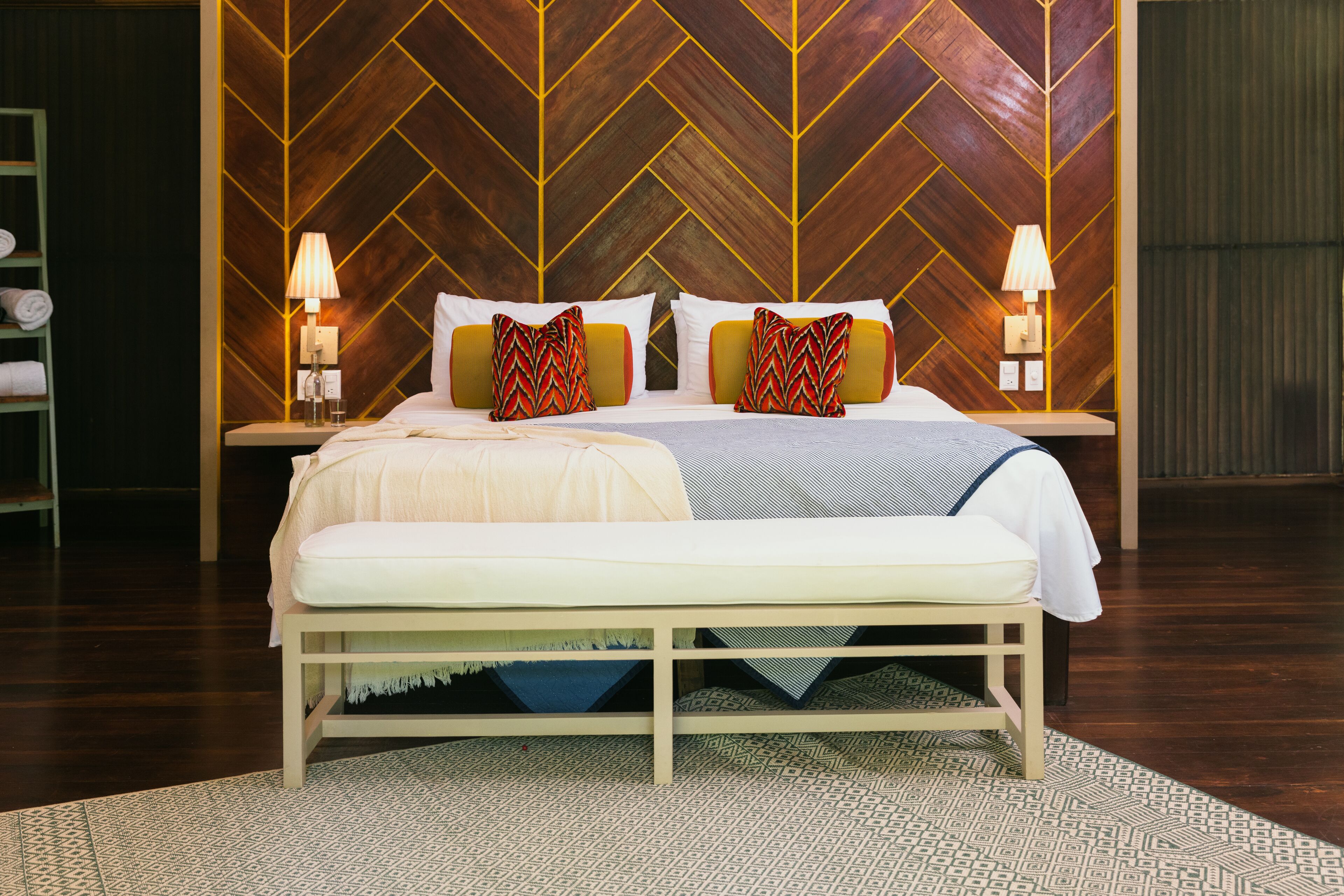 A double bed with a wooden headboard, two bedside tables with lamps, and a patterned rug.