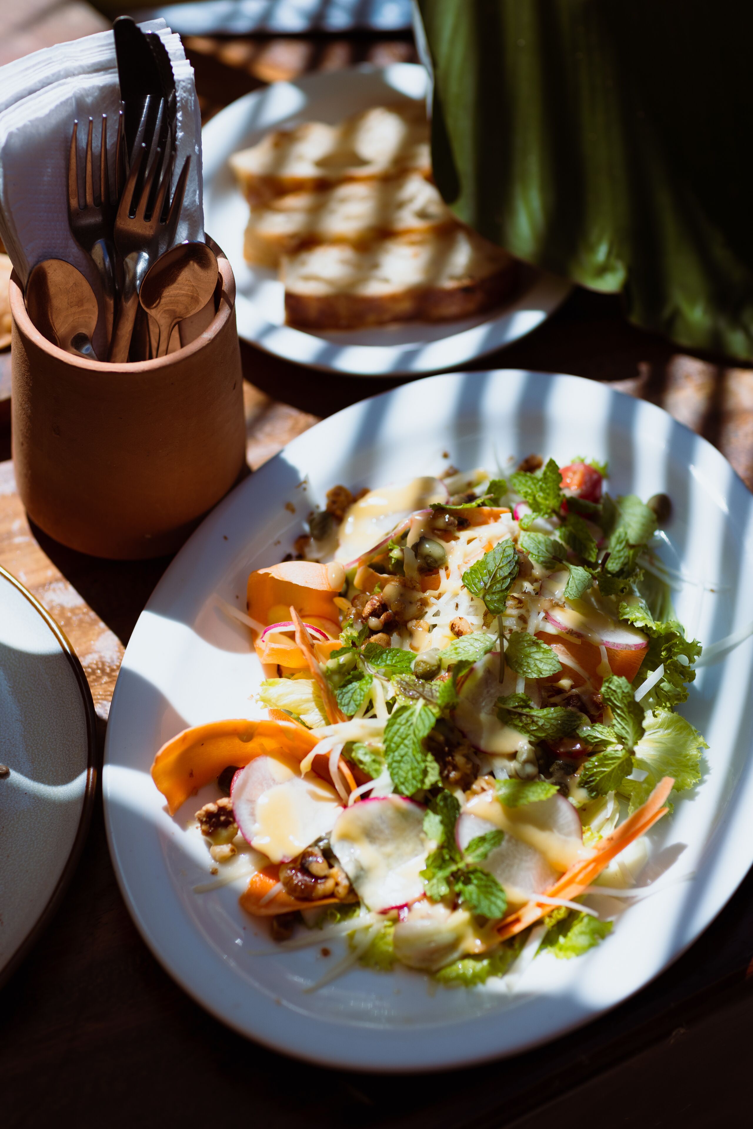 A plate of food with a variety of vegetables and a cup with utensils.