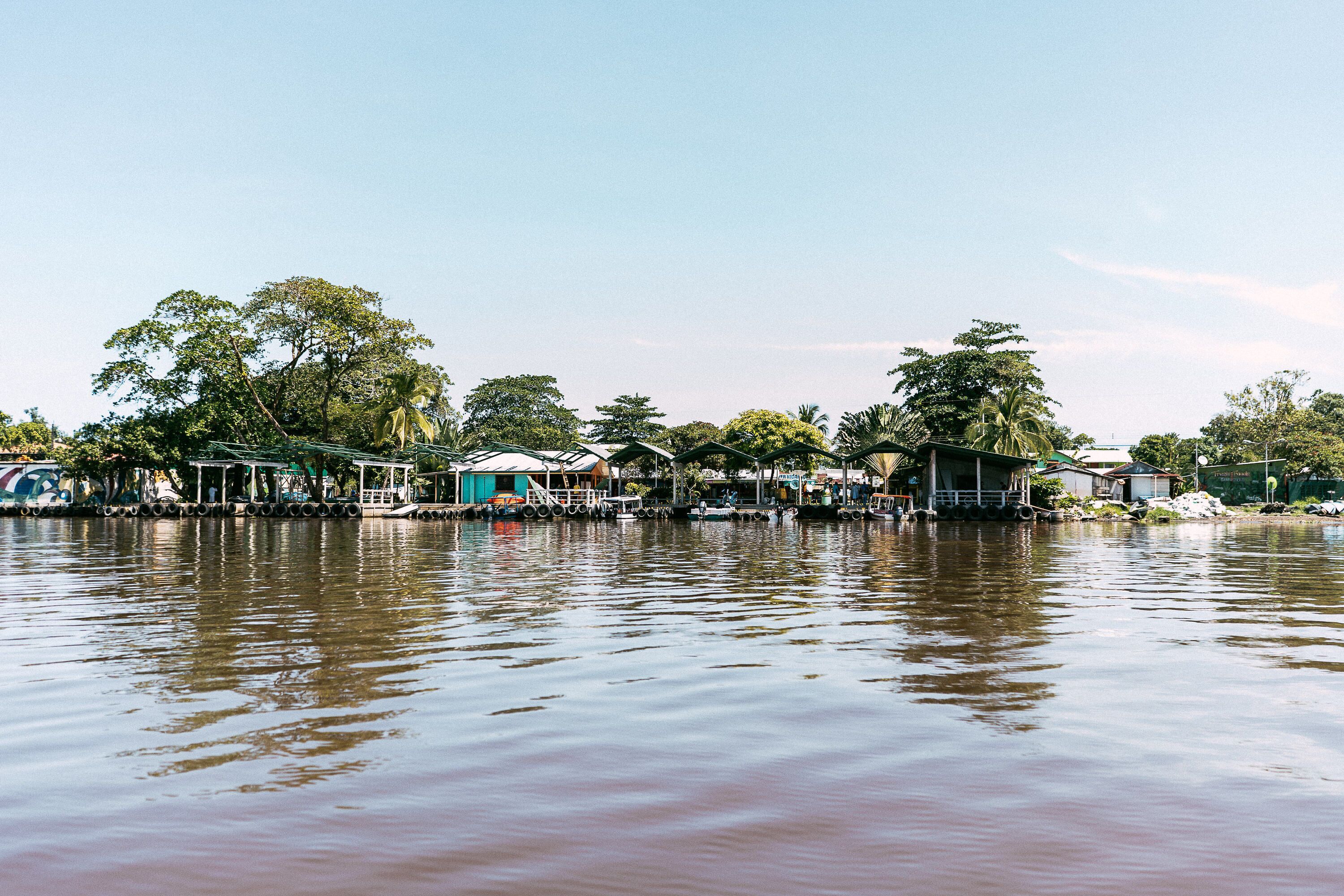 A riverside area with floating structures, likely for accommodation or dining, surrounded by trees and calm water.