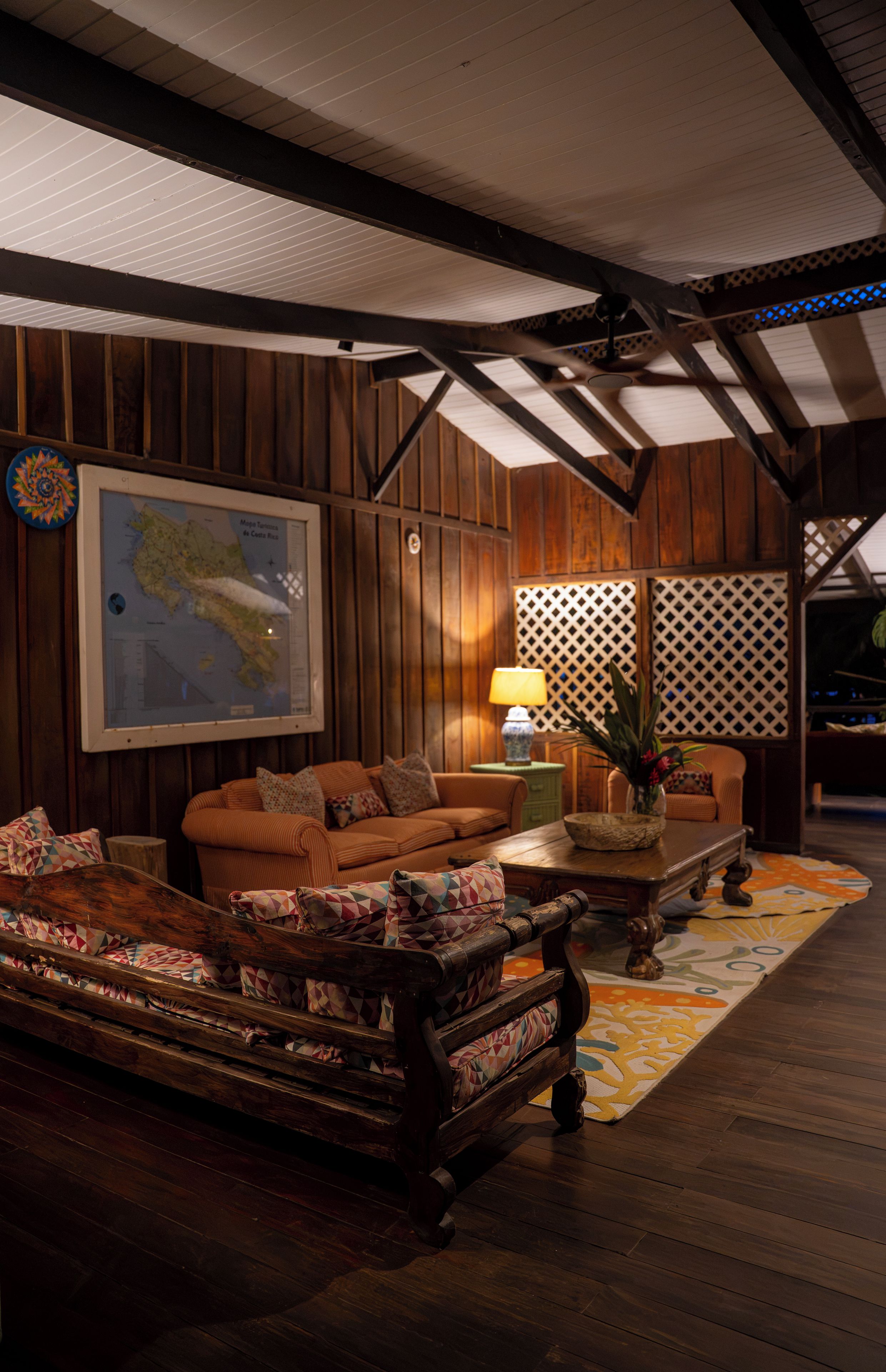 A room with wooden paneling, a map on the wall, a sofa, a coffee table, and a patterned rug.