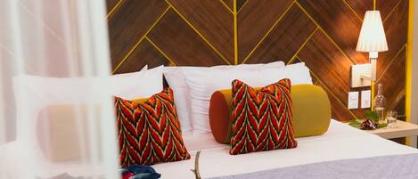 A bedroom with a bed, pillows, a bedside table, and a lamp.