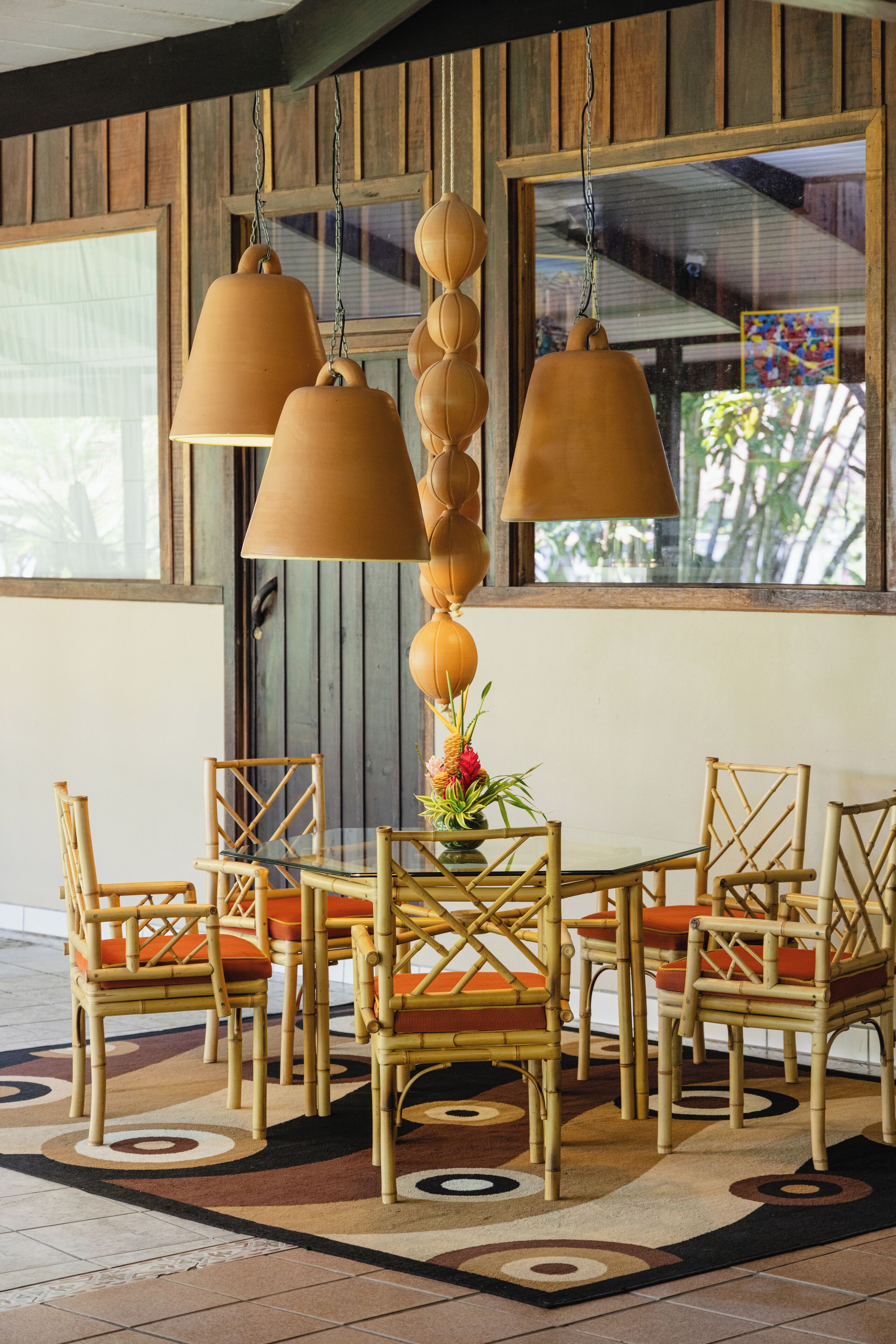 A dining area with wicker chairs and a table, a hanging light fixture, and a window with a view.