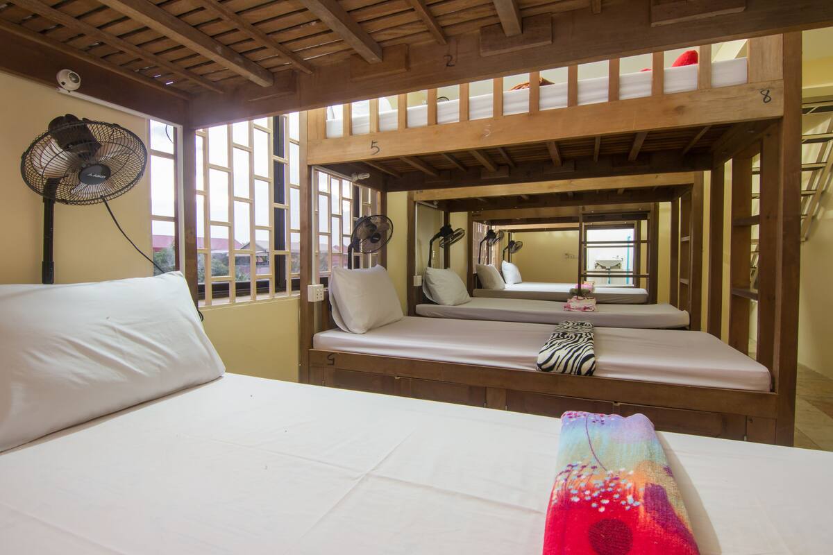 A room with a bunk bed, a single bed, and a window with a view.