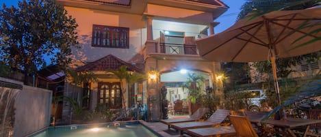 A two-story house with a swimming pool, outdoor furniture, and a balcony.
