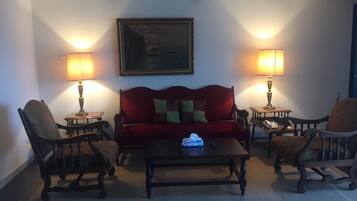 A cozy living room with a red sofa, two armchairs, a coffee table, and two lamps.