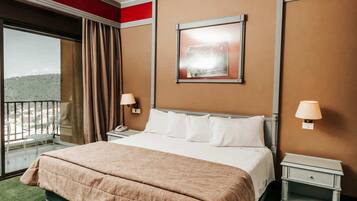 Une chambre d’hôtel avec un grand lit, deux tables de chevet, une fenêtre avec vue et un mur d’accent de couleur rouge.