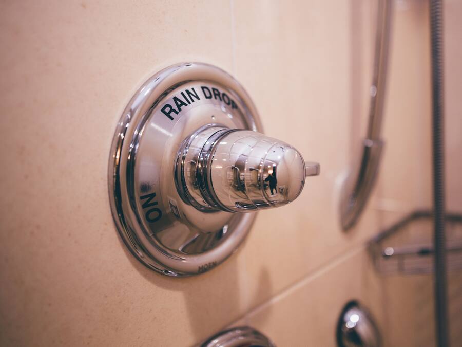 A bathroom with a shower head and a hand dryer.