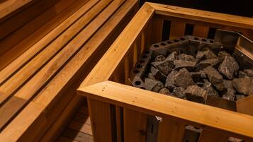 Una sauna con bancos de madera y una rejilla metálica llena de piedras.