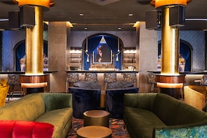 A bar area with a large screen, plush seating, and a patterned wall.