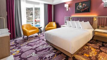 A hotel room with a large bed, two armchairs, a small table, and a view of a snowy landscape through the window.