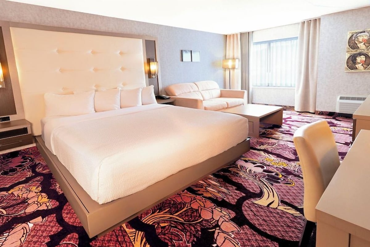 Una habitación de hotel con una cama grande, un sofá, un escritorio y una silla.