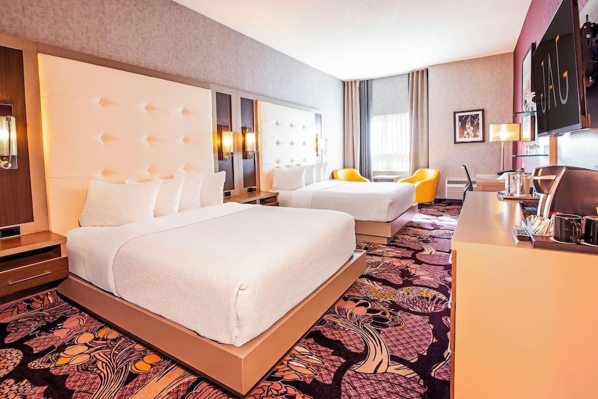 Una habitación de hotel con una cama grande, una cama más pequeña, un escritorio y una silla.