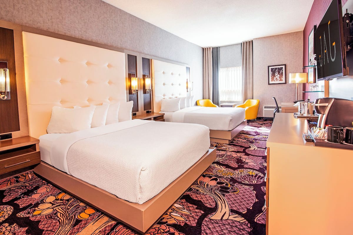 A hotel room with a large bed, two bedside tables, a desk, a chair, and a television.