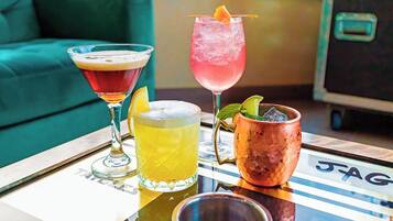 Trois boissons sont posées sur une table, avec un canapé et un meuble en arrière-plan.