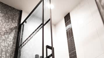 A modern shower with a glass door and a ceiling-mounted rain showerhead.