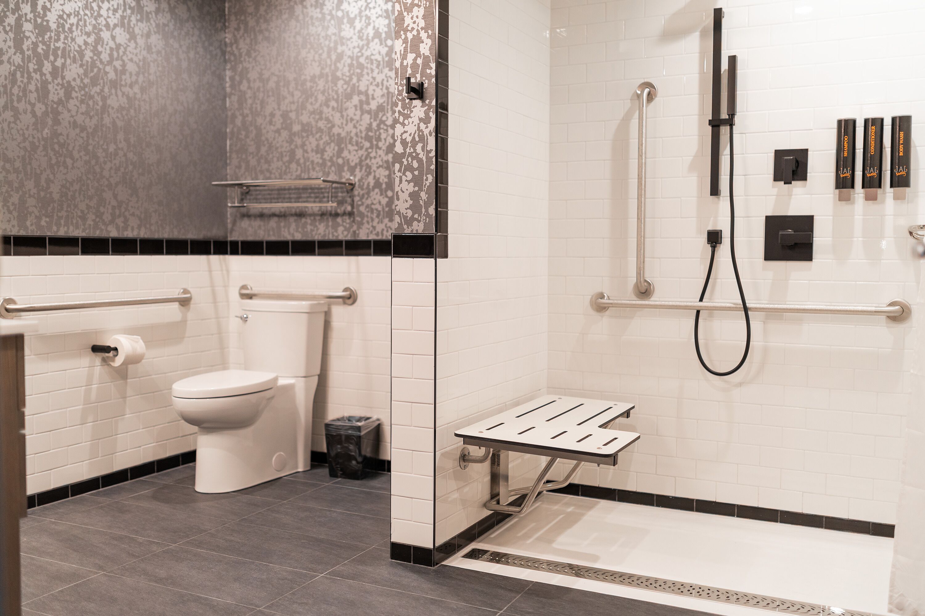 Une salle de bain moderne comprenant des toilettes, un espace douche avec un pommeau de douche à main et un porte-serviettes.