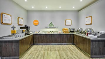 A buffet area with breakfast options, coffee machines, and a variety of food items.