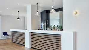 Uma área de recepção moderna com balcão de ripas de madeira, duas luminárias pendentes e um aplique de parede.