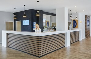 A hotel reception area with a modern design, featuring a reception desk, a bar area, and a counter with various amenities. - Holiday Inn Express Grimsby by IHG (Grimsby)