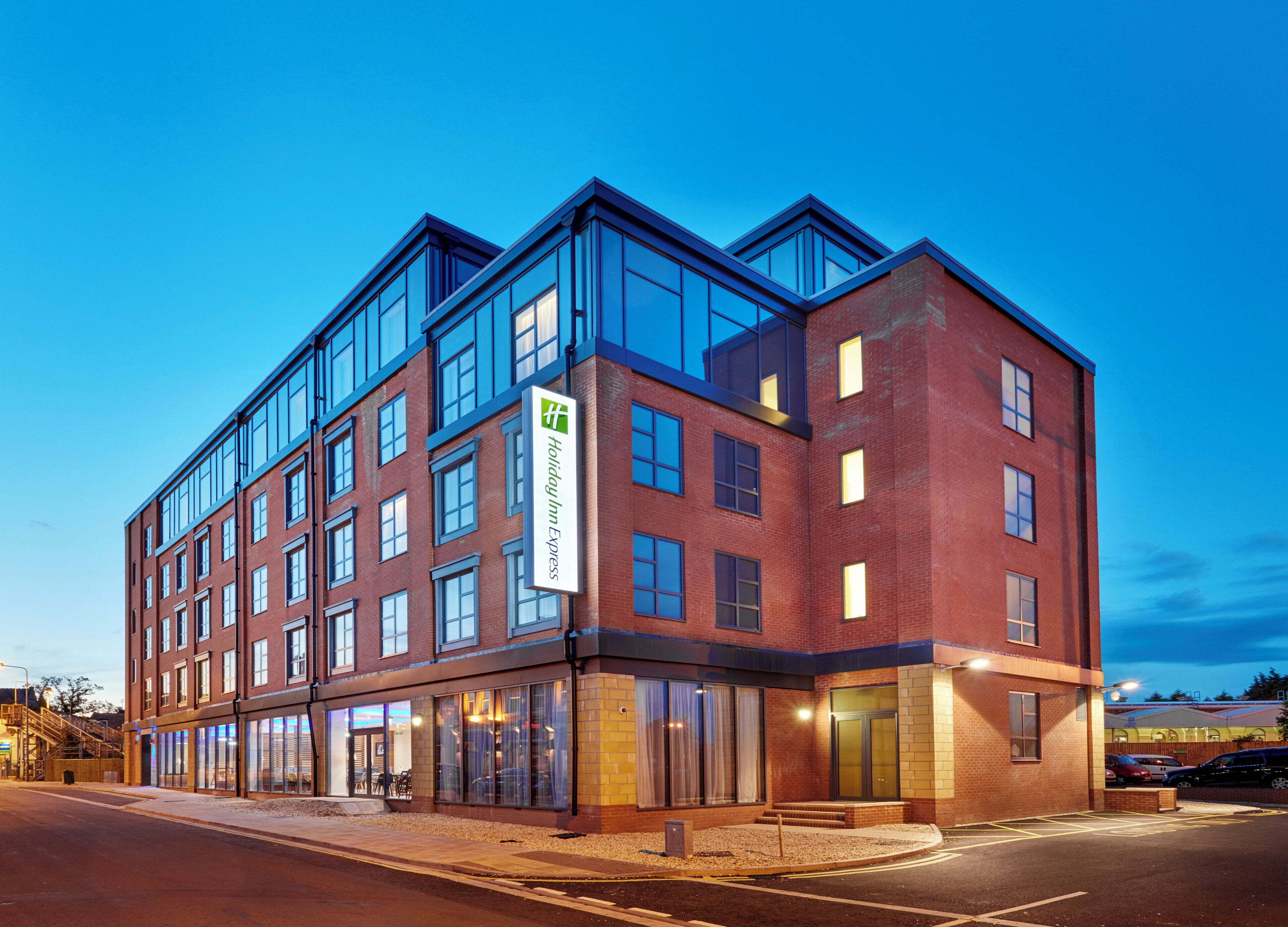 Un hôtel à plusieurs étages, reconnaissable à son grand panneau « Holiday Inn Express », à ses larges fenêtres et à sa façade en briques.