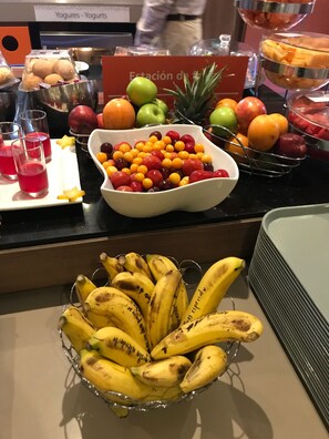 Un bufé con diversas frutas y un bol de plátanos.