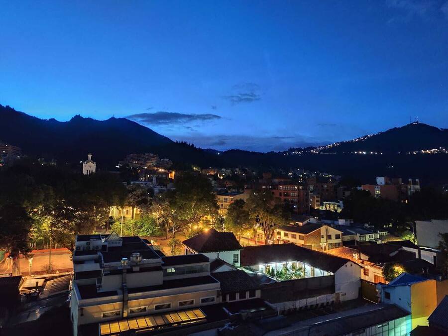 Un pueblo al anochecer, con edificios y una montaña de fondo.